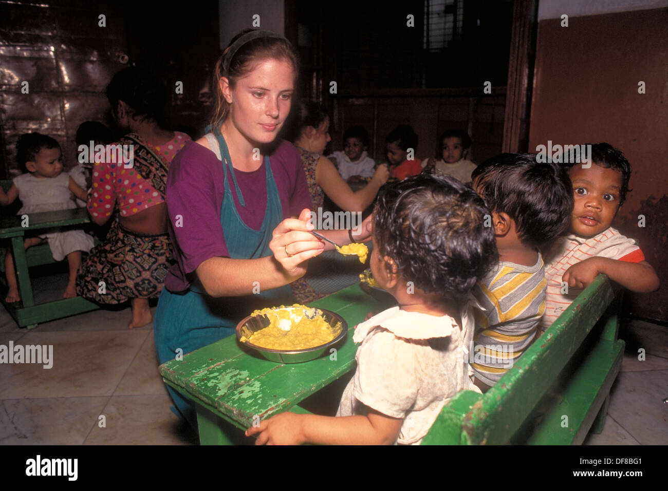 Mutter Teresa Freiwillige, Kari Amber Mcadam speist drei Waisenkinder zur gleichen Zeit im Shishu Bhavan, das erste Waisenhaus. Stockfoto