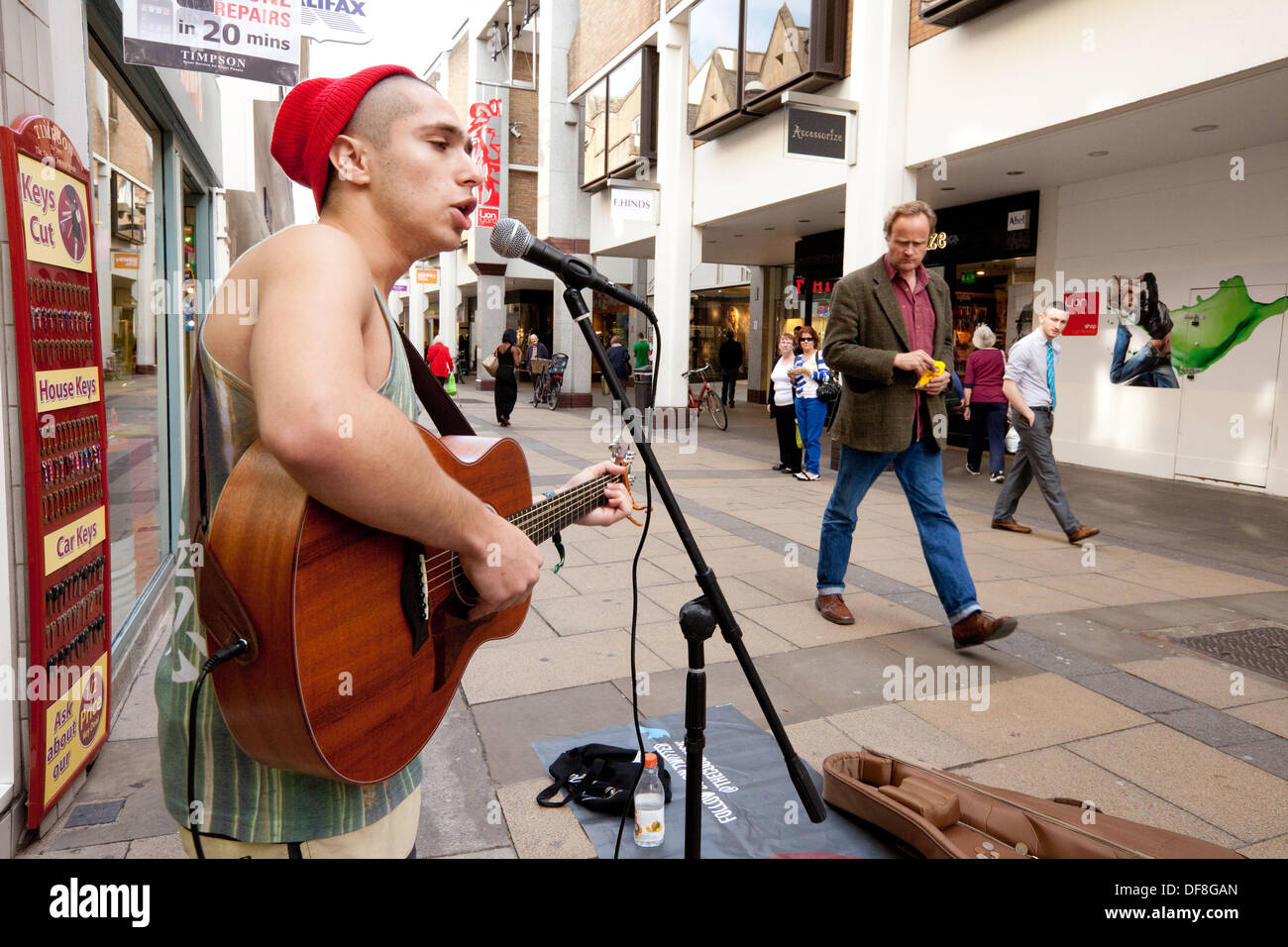 Straßenkünstler in Großbritannien; männlicher Straßenmusiker, der Gitarre spielt und singt, Lion Yard, Cambridge City Centre in Großbritannien Stockfoto