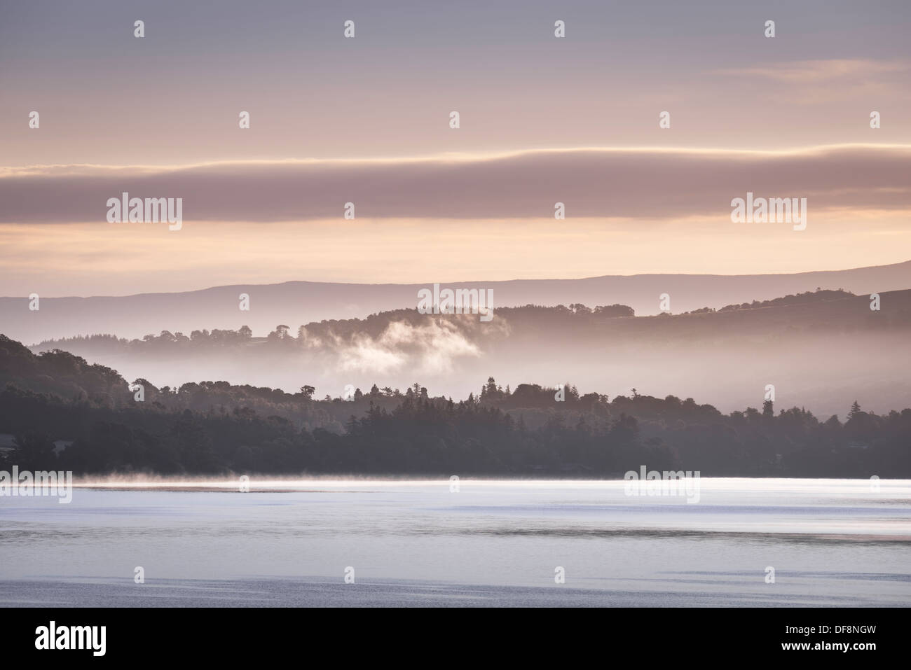 Schleier der Nebel im Tal hängen und steigen von der Oberfläche des Ullswater in Küstennähe an der ersten Ampel. Stockfoto