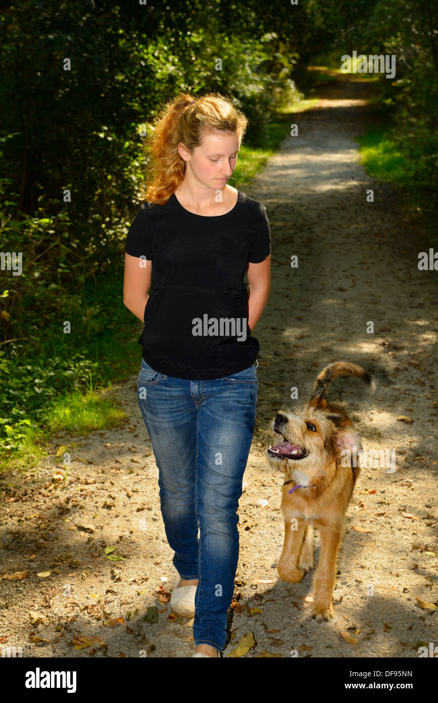 Junge Frau zu Fuß einen aufmerksamen Hund auf einem Weg in einem Wald von Toronto Stockfoto