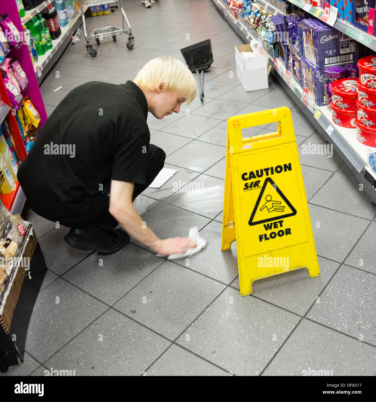 Vorsicht nassen Boden: Ein junger Mann, arbeiten, Aufräumen ein Spritzer  auf dem Boden eines Supermarktes, UK Stockfotografie - Alamy
