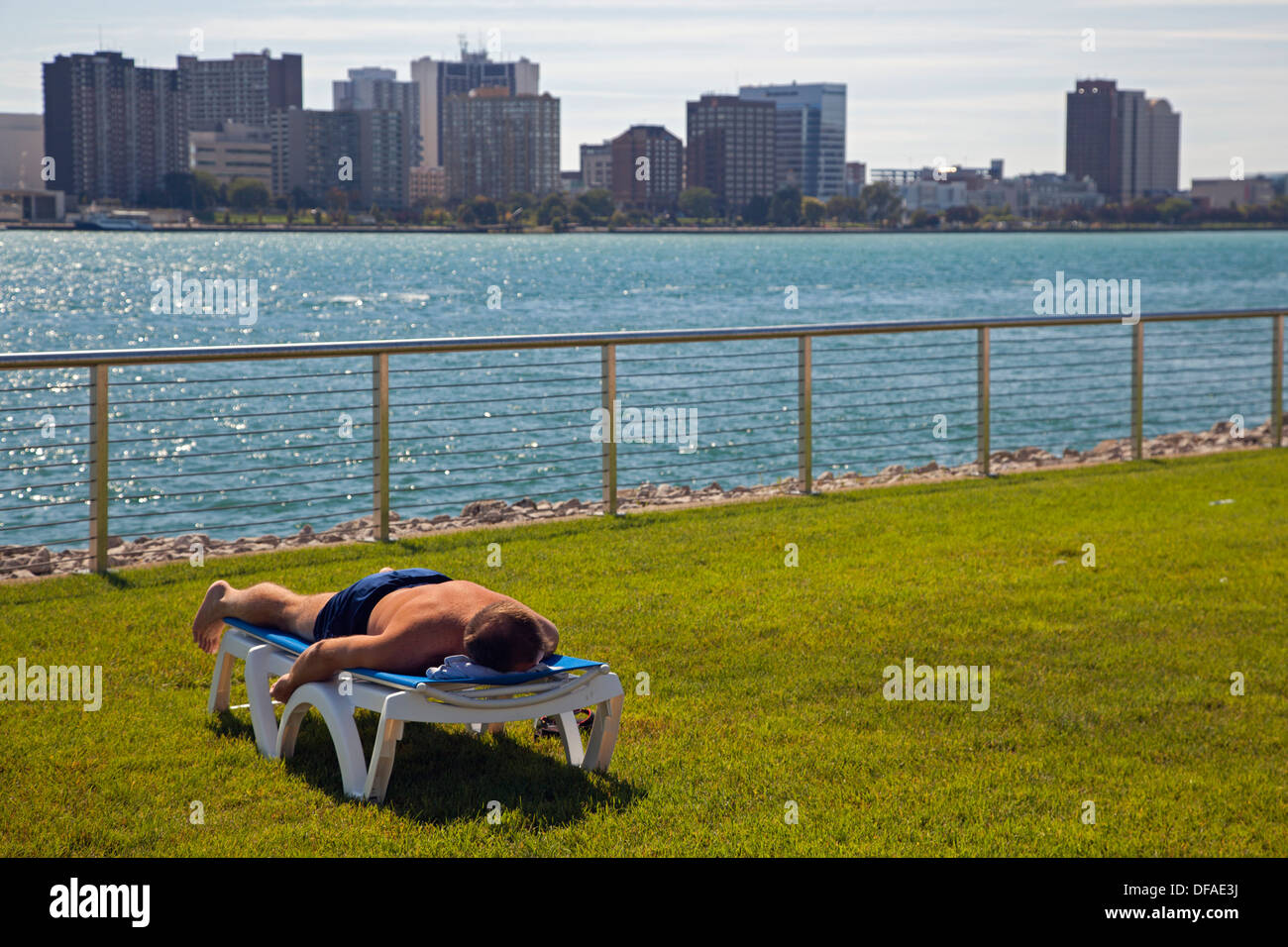 Detroit, Michigan - ein Mann arbeitet an seiner Bräune liegend auf einem Stuhl in der Nähe von den Detroit River. Stockfoto