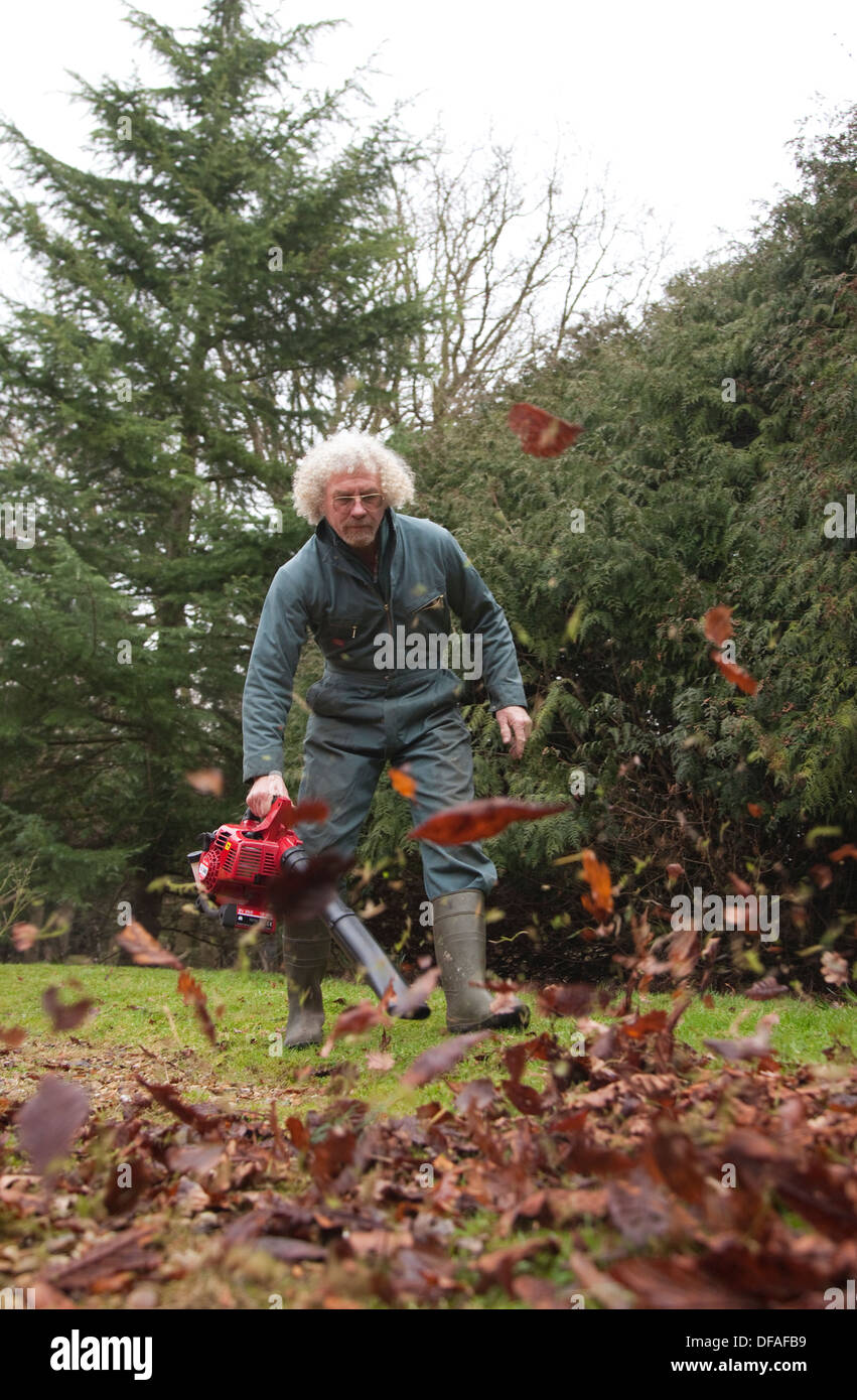 Ein Mann verwendet einen Laubbläser in Garten Großbritannien Stockfoto