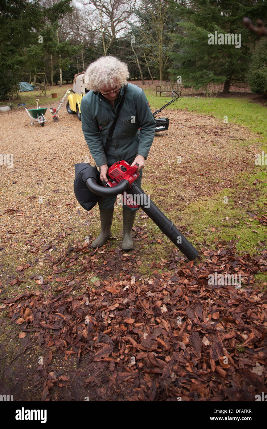Ein Mann verwendet einen Laubbläser in Garten Großbritannien Stockfoto