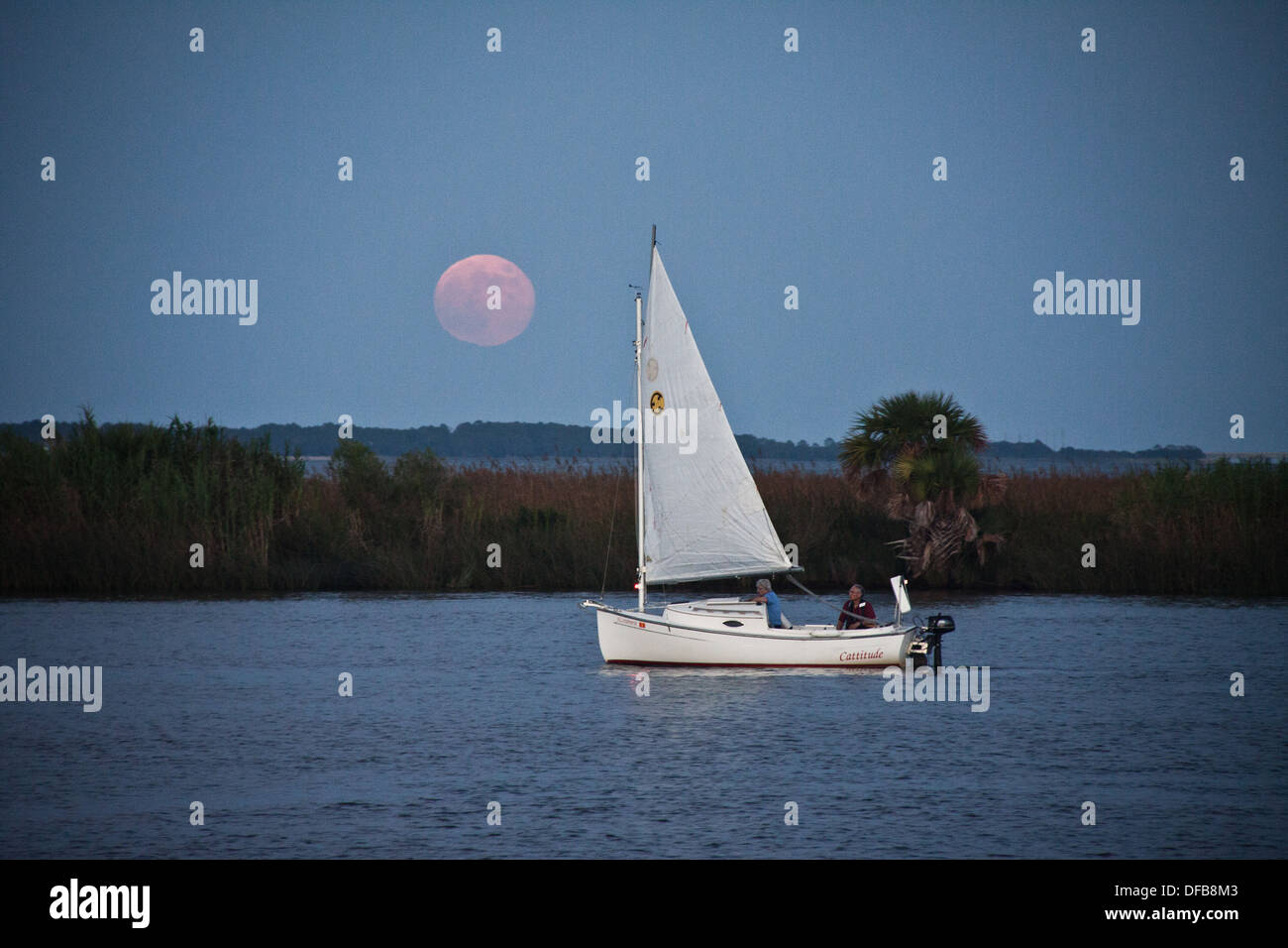 Kleines Segelboot bewegt den Fluss hinauf in Apalachicola, Florida, als der Vollmond steigt Stockfoto