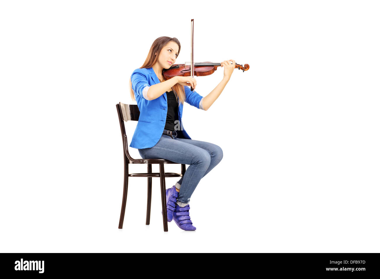 Lässige junge Frau sitzend auf einem Holzstuhl, Geige zu spielen Stockfoto