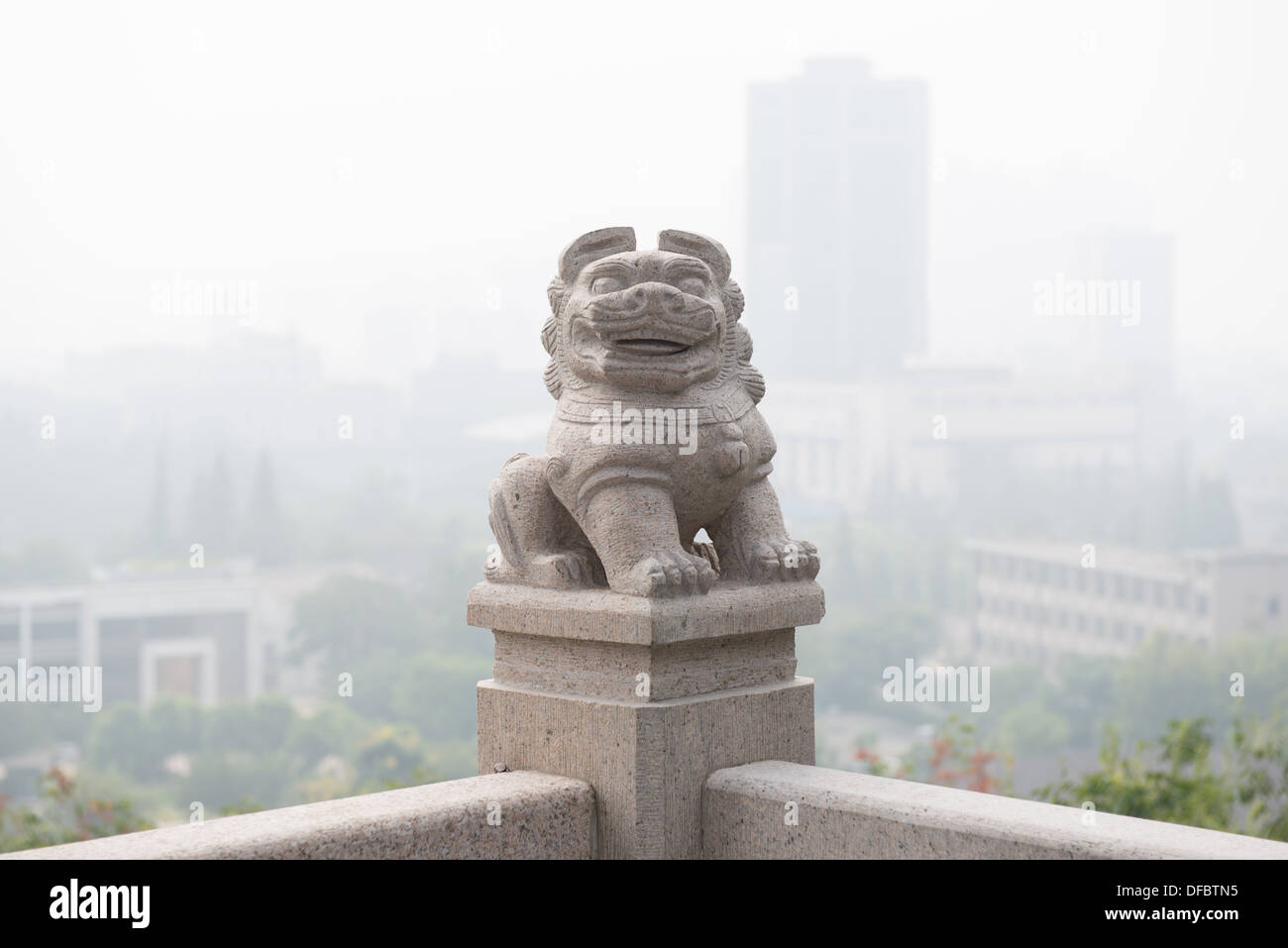Yuejiang Lou, Nanjing, China. Statue eines Löwen auf eine Balustrade mit der Skyline der Stadt im Hintergrund. Stockfoto