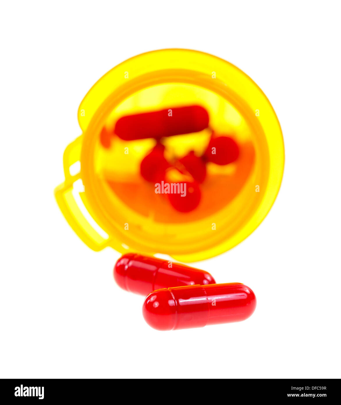 Zwei Antibiotika-Kapseln vor einem gelben Medizinfläschchen mit dem Rest der Dosierung in der Flasche. Stockfoto