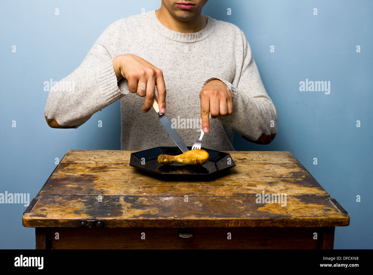 Junger Mann isst ein Hühnerbein Stockfoto