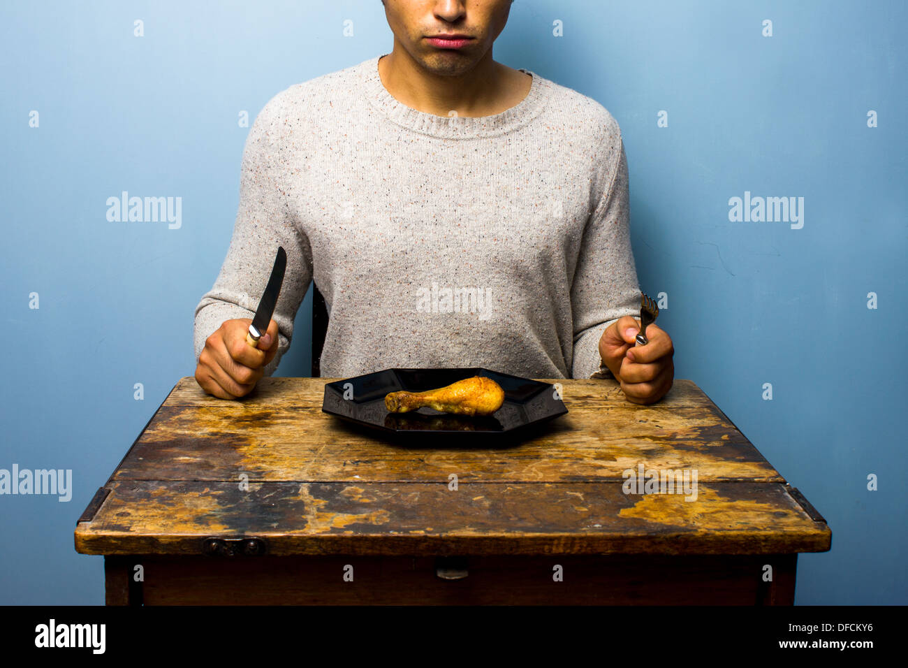 Junger Mann isst ein Hühnerbein Stockfoto