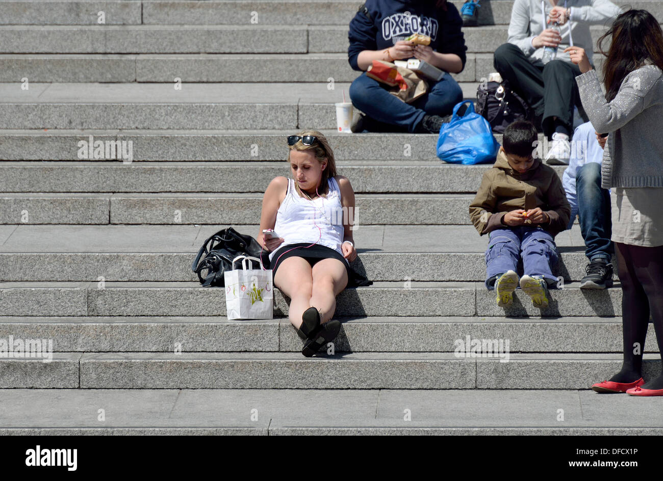 London, England, Vereinigtes Königreich. Trafalgar Square - junge Frau entspannen Sie sich auf die Schritte, Musik hören Stockfoto