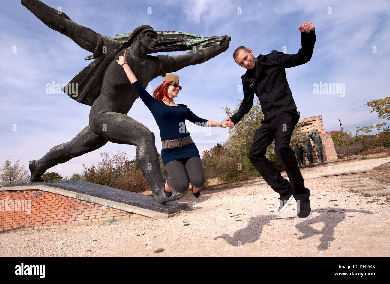 Ungarische Mann und Frau vor Denkmal zu springen, während des Besuchs Memento Statue Park in Budapest, Ungarn Stockfoto