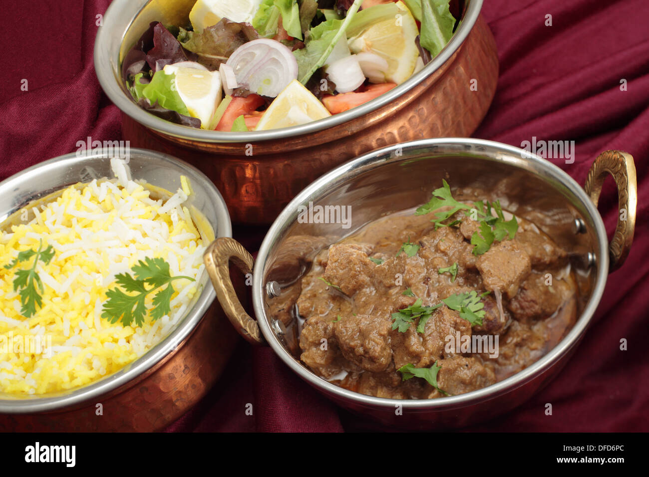 Indische Kupfer Gerichte mit Rindfleisch Rogan Josh, weißen und gelben Reis und Salat Stockfoto