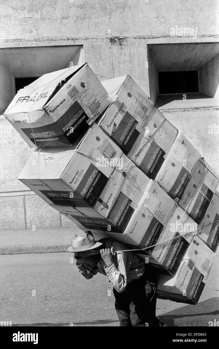 Guatemala City Mittelamerika. 1973. Rückwärtsbrechender Arbeiter, der Schreibmaschinenboxen von Remington Standard trägt. 1970er Jahre HOMER SYKES Stockfoto