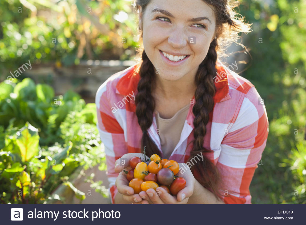 Lächelnde Frau mit Handvoll Kirschtomaten Stockfoto