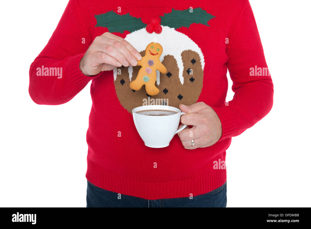 Mann trägt einen Weihnachtspullover, Tauchen Sie einen Lebkuchenmann in eine Tasse heiße Schokolade, isoliert auf einem weißen Hintergrund. Stockfoto