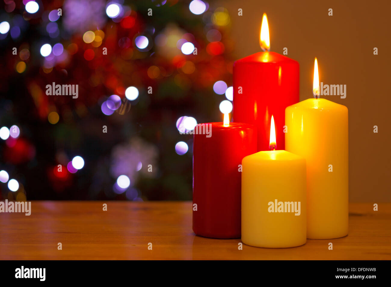 Vier Kerzen brennen mit der Fokuslichter von einem Weihnachtsbaum hinter. Stockfoto