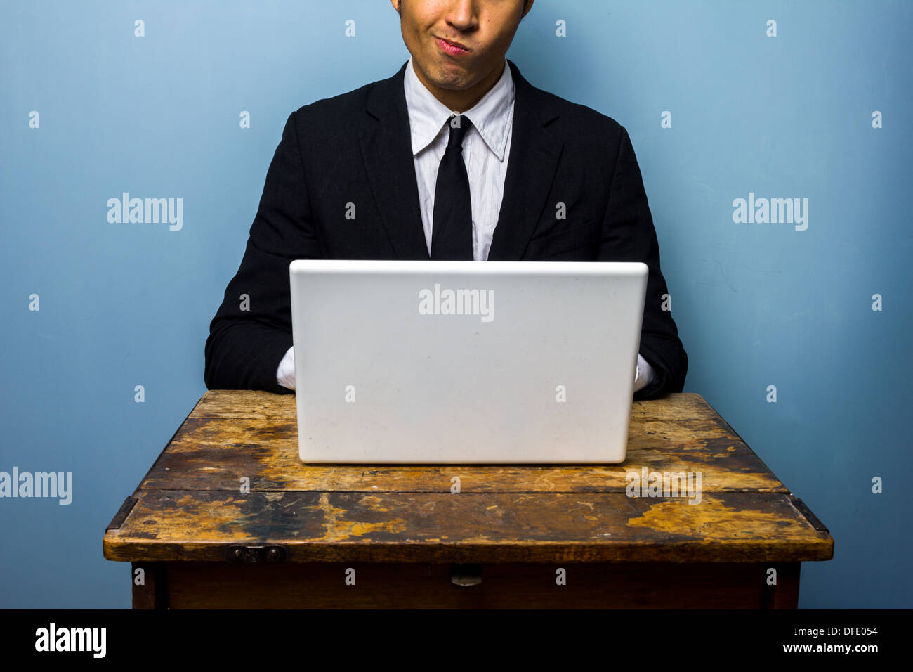 Verwirrter jungen Geschäftsmann nutzt seinen Laptop auf einem alten Schreibtisch Stockfoto
