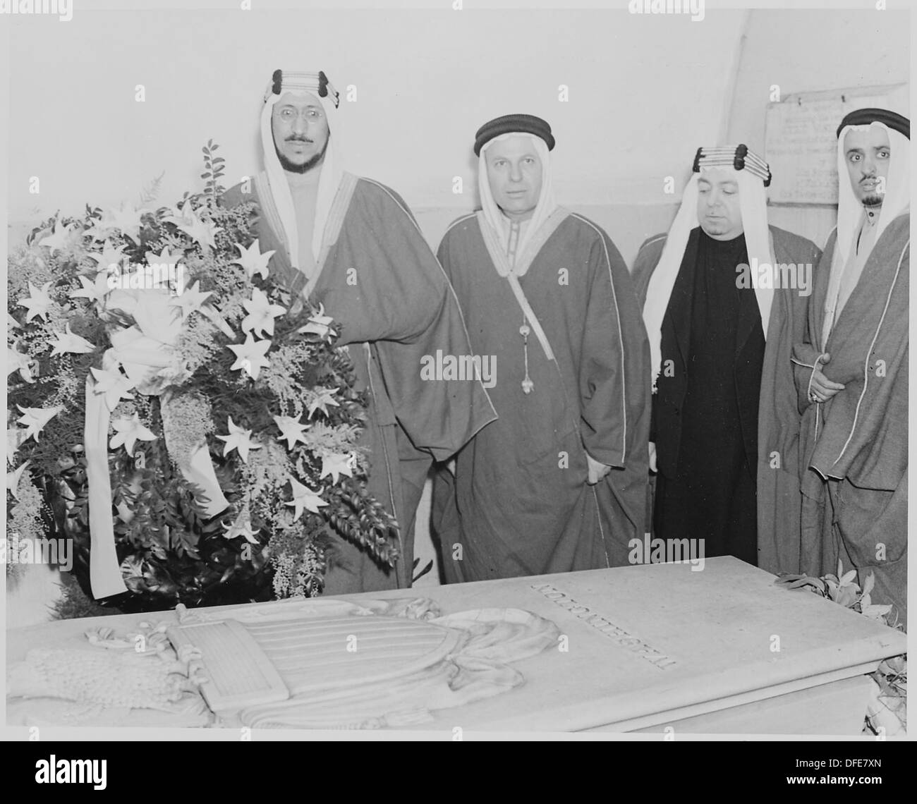 Ein historisches Foto, das Kronprinz Amir Saud von Saudi-Arabien zusammen mit drei Würdenträgern zeigt, wie sie einen Kranz an einer bedeutenden Stelle legen. Dieses Bild fängt einen offiziellen diplomatischen Moment ein. Stockfoto