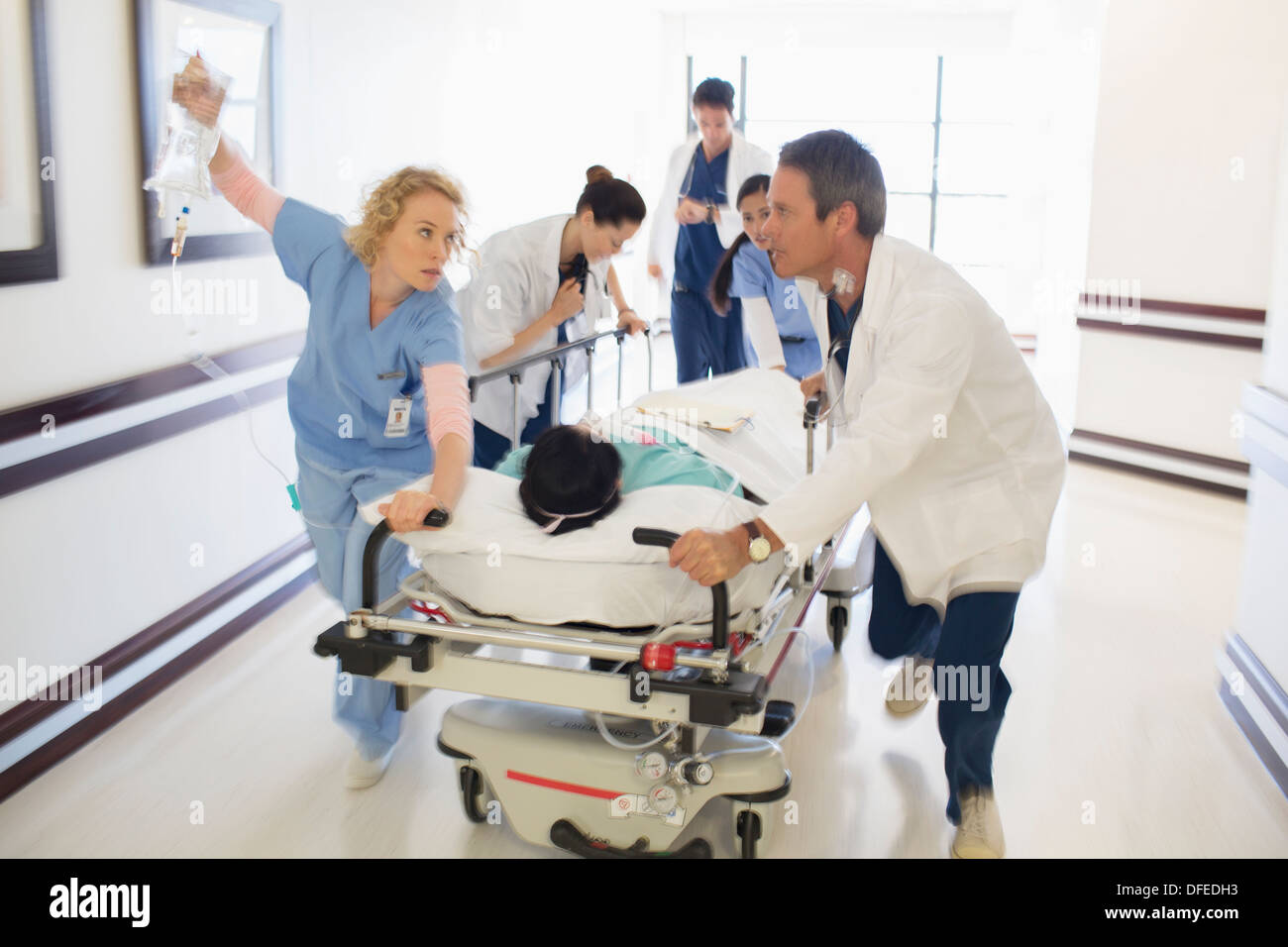 Ärzte, die Patienten auf Bahre im Krankenhausflur Rauschen Stockfoto