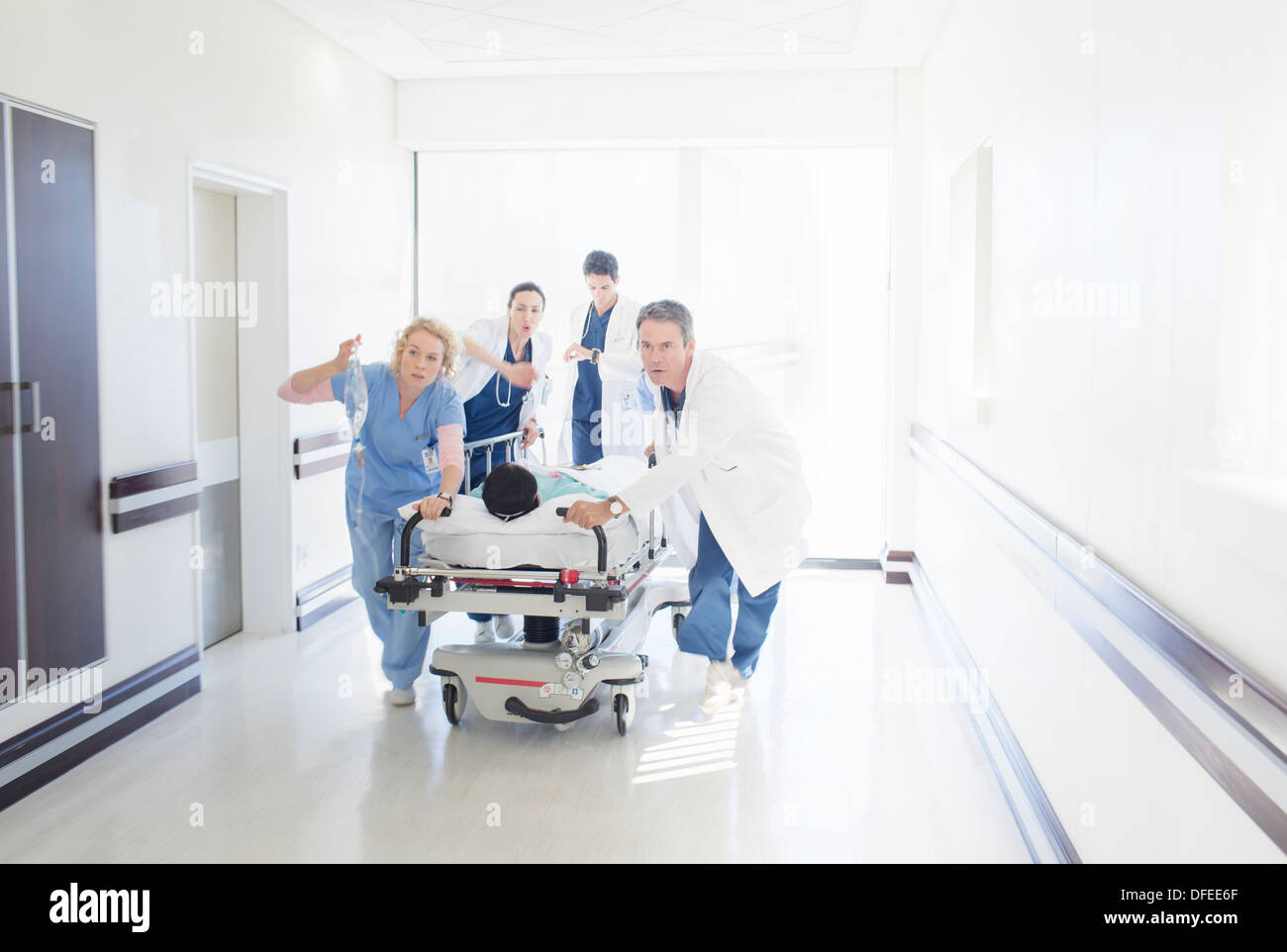 Ärzte und Krankenschwestern, die Patienten auf trage unten Krankenhausflur Rauschen Stockfoto