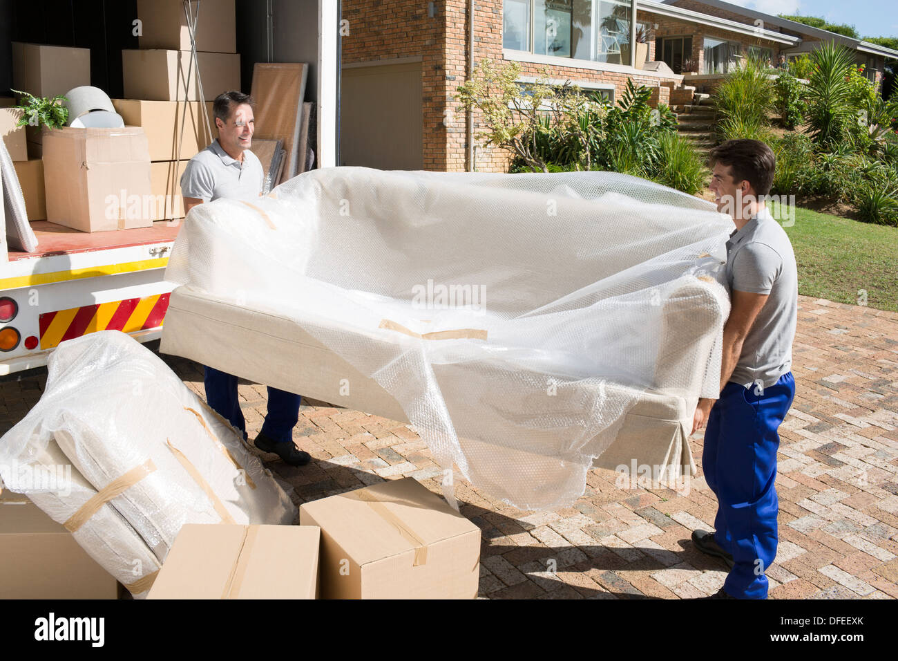 Mover mit Sofa von Möbelwagen in Einfahrt Stockfoto