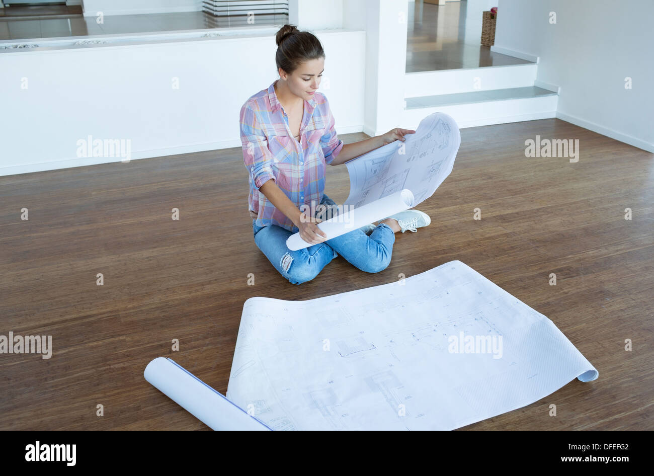 Frau Prüfung Blaupausen in leeren Wohnzimmer Erdgeschoss Stockfoto