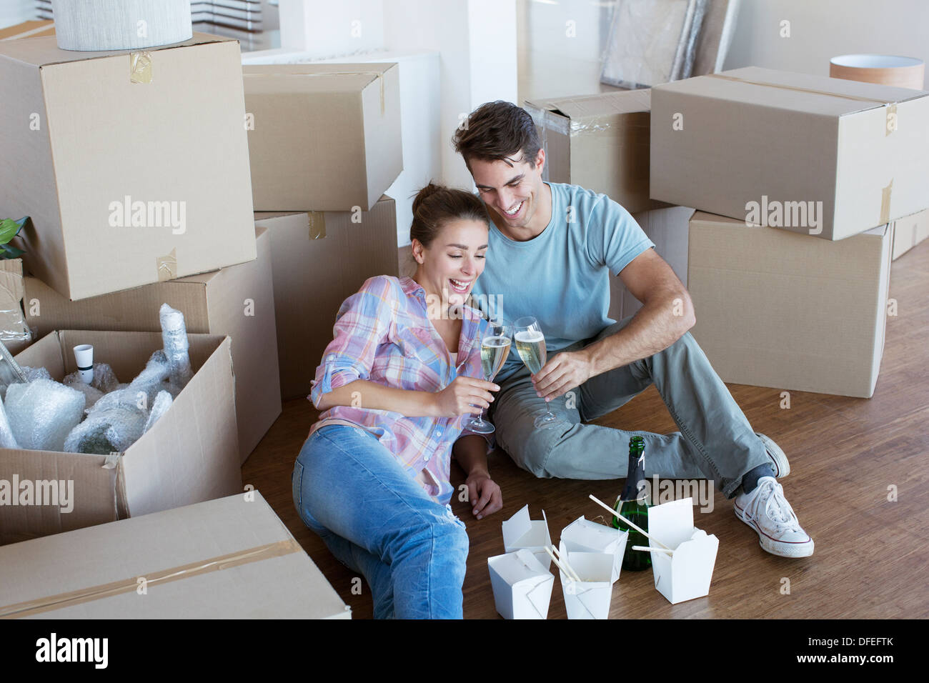Paar genießt Champagner und Chinesen nehmen Sie Essen im neuen Haus Stockfoto