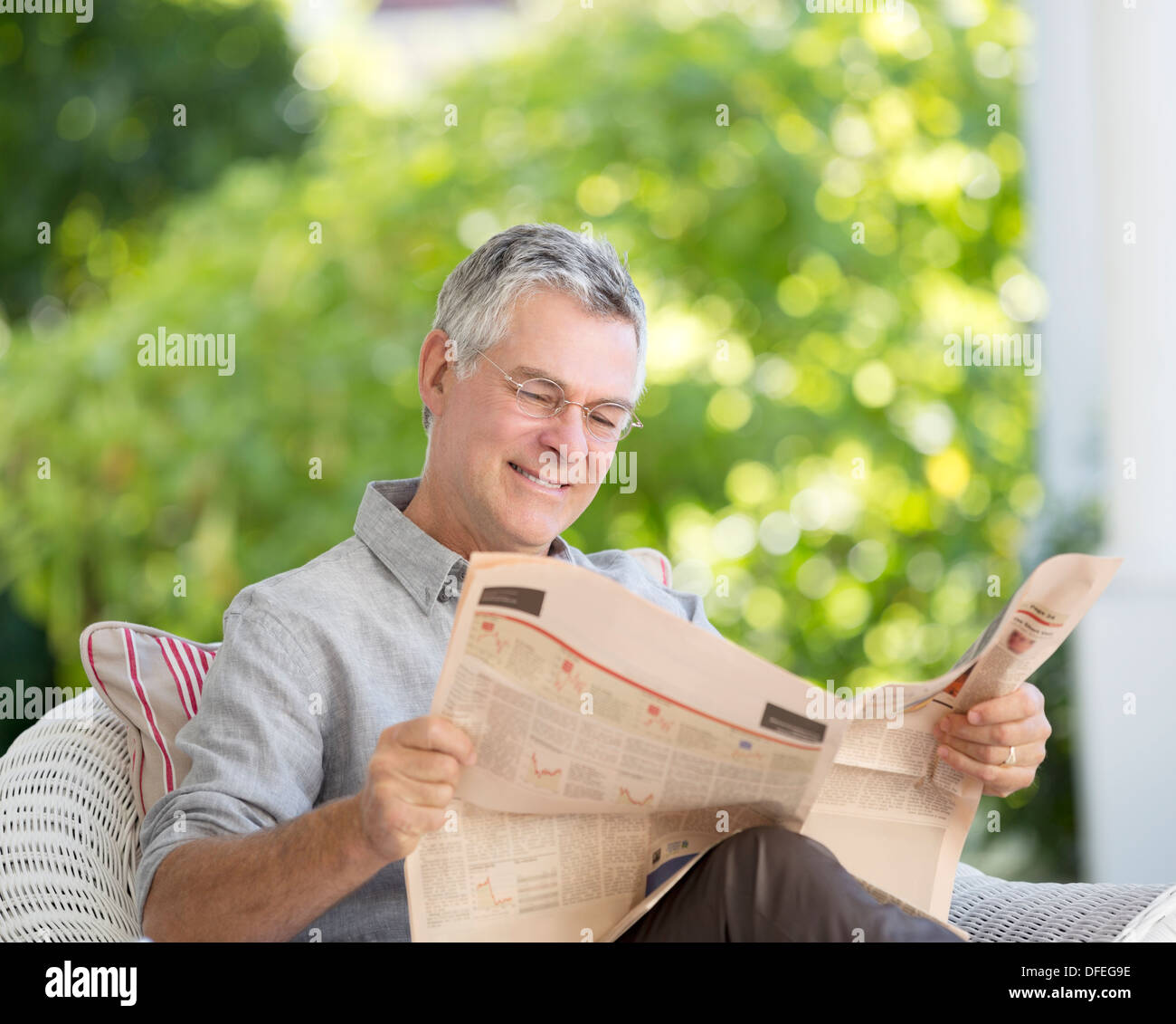 Ältere Mann liest Zeitung auf Terrasse Stockfoto