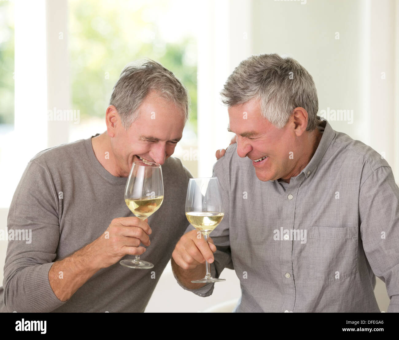 Senioren Herren Lachen und trinken Weißwein Stockfoto
