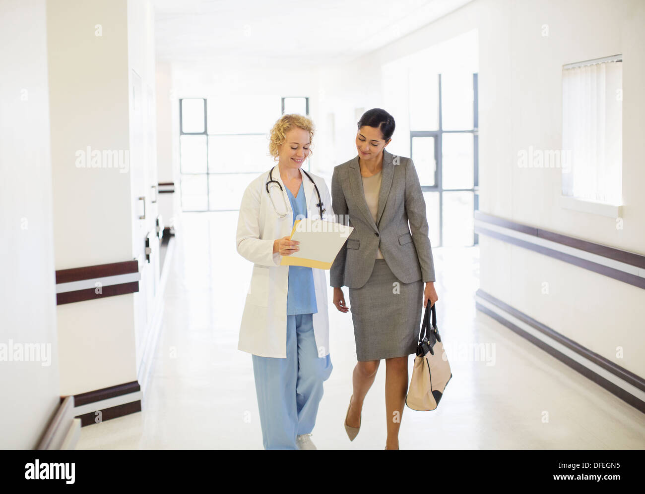 Arzt und Geschäftsfrau im Krankenhausflur sprechen Stockfoto