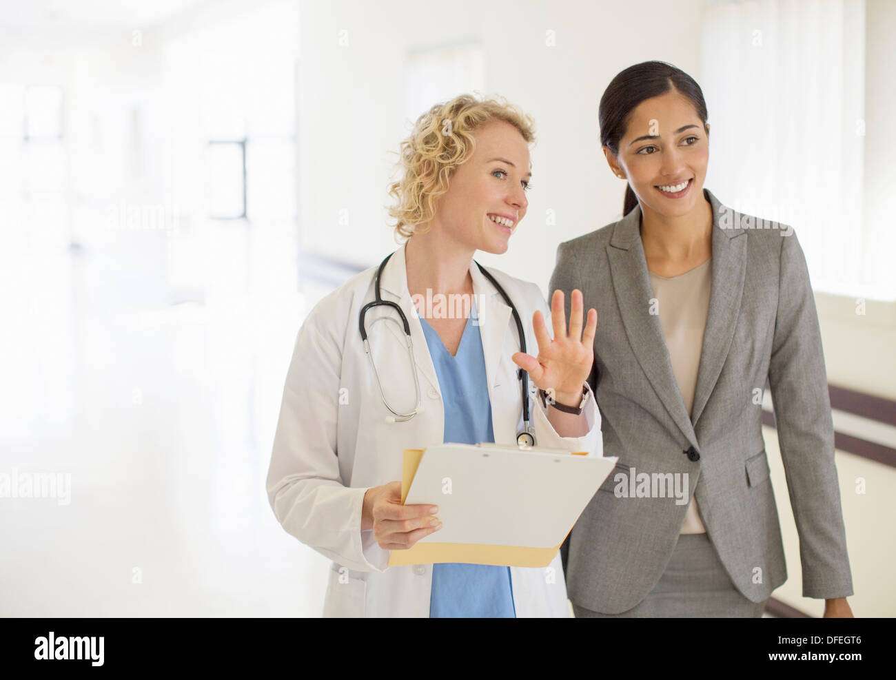 Arzt und Geschäftsfrau im Krankenhausflur sprechen Stockfoto