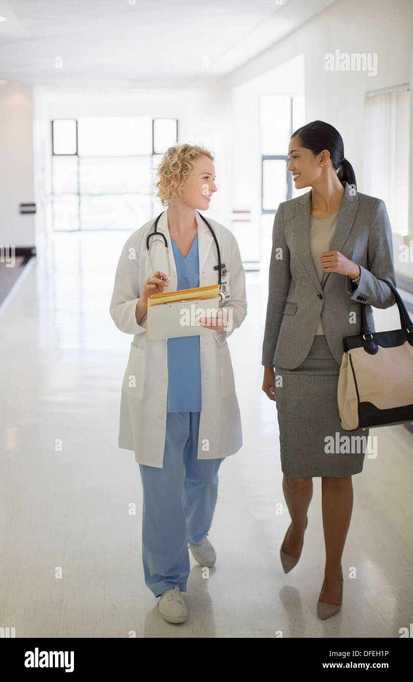 Arzt und Geschäftsfrau im Krankenhausflur spazieren Stockfoto