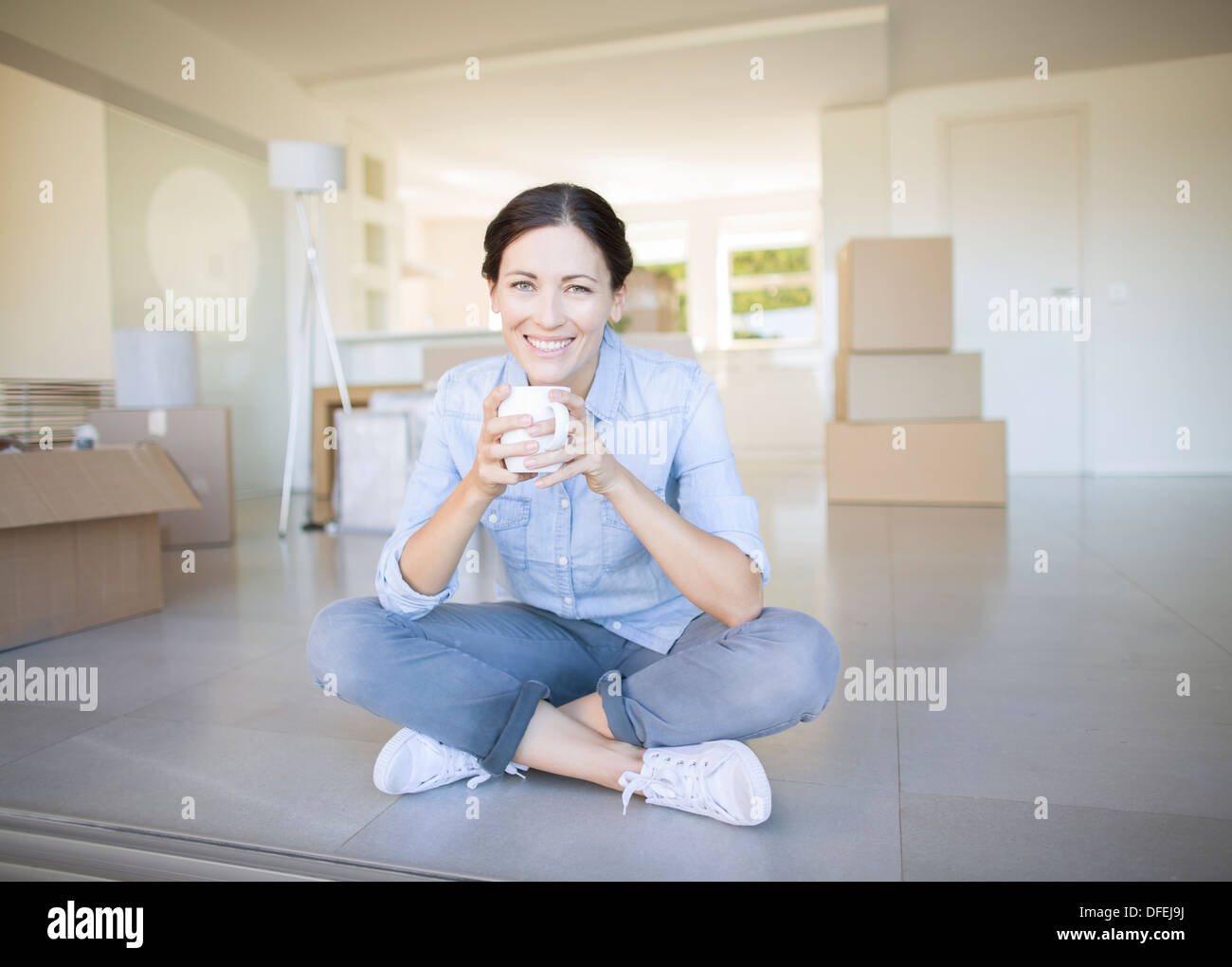 Frau trinkt Kaffee unter Kartons Stockfoto