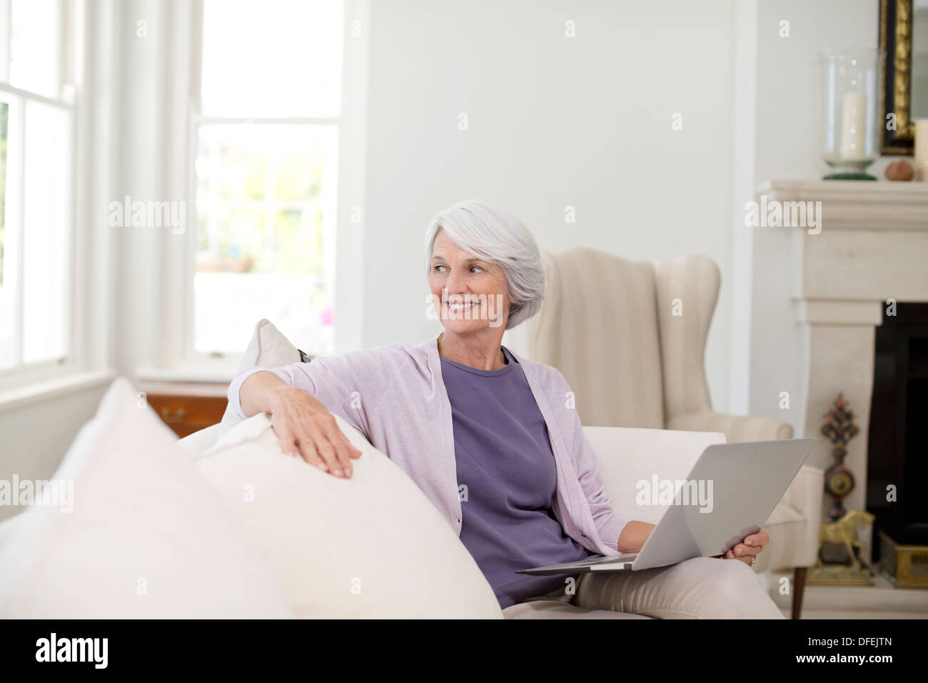 Ältere Frau mit Laptop auf sofa Stockfoto