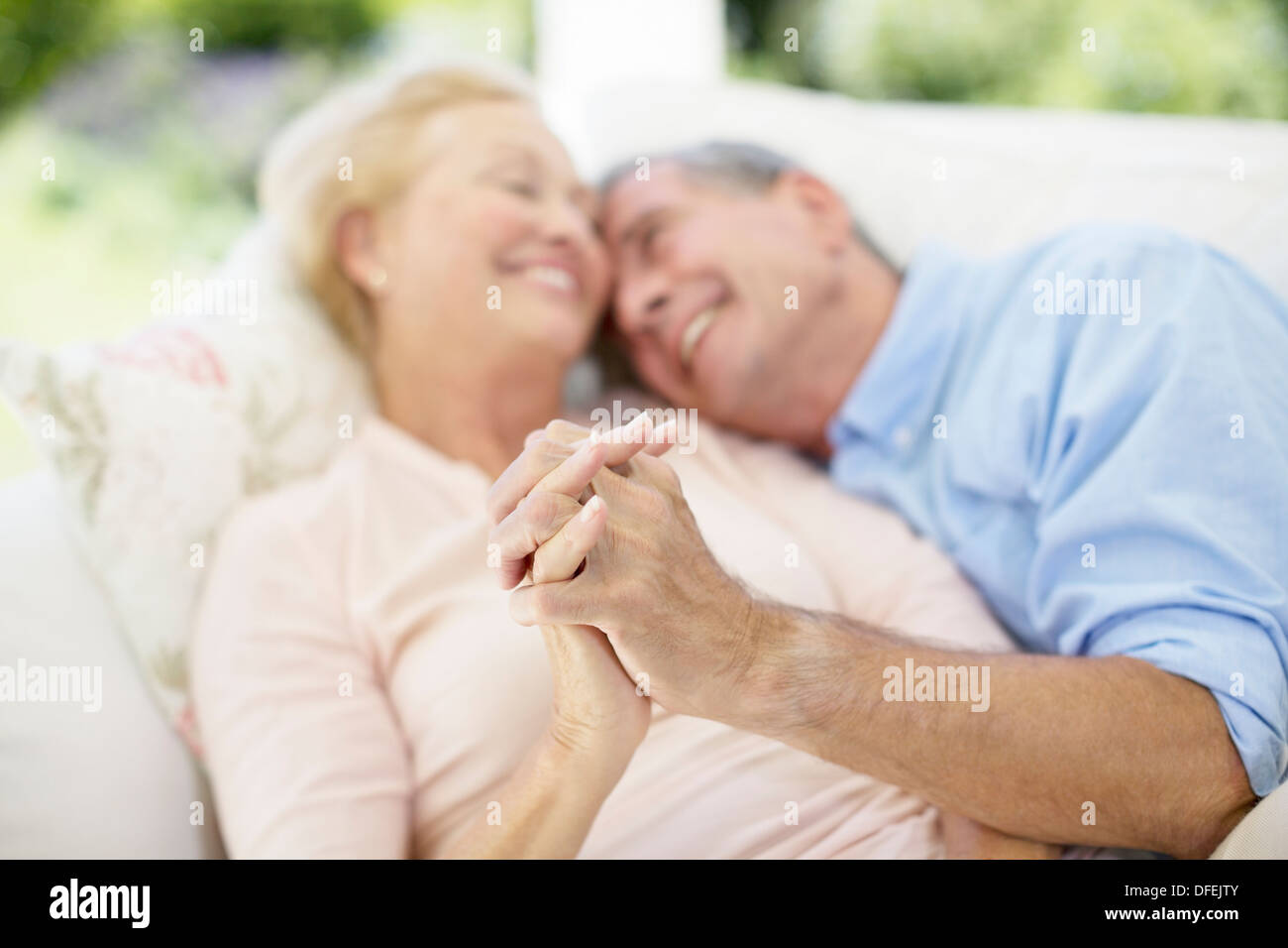 Älteres Paar halten die Hände auf sofa Stockfoto