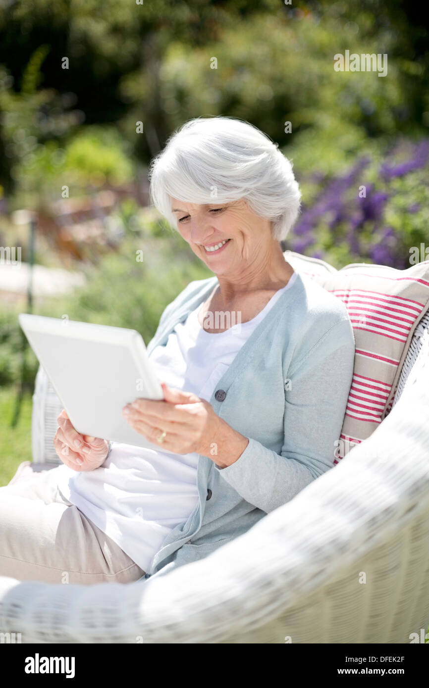Ältere Frau mit digital-Tablette in Sessel Stockfoto