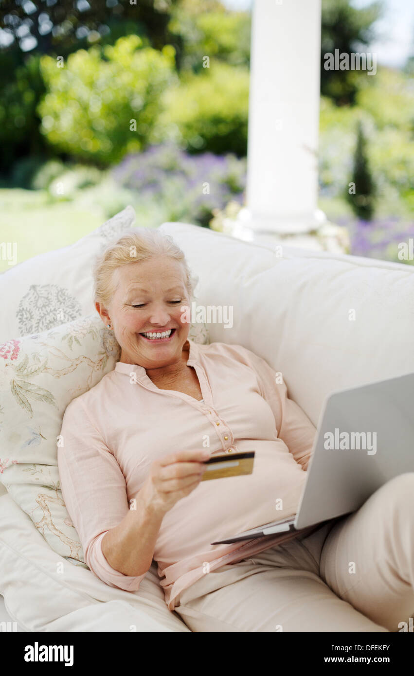 Ältere Frau, Online-shopping auf Terrasse sofa Stockfoto