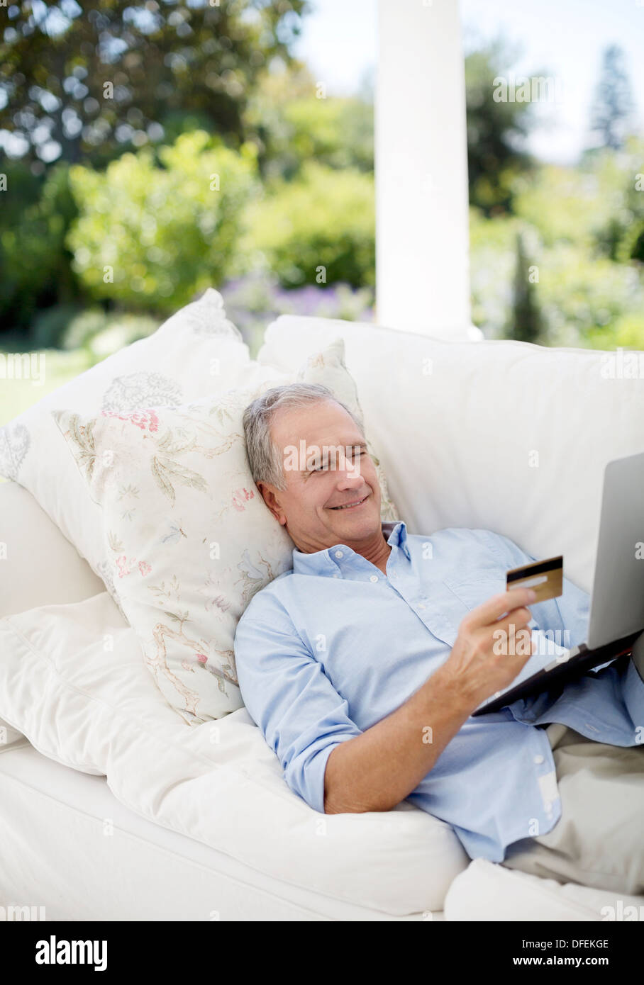 Senior Woman online-shopping auf Terrasse sofa Stockfoto