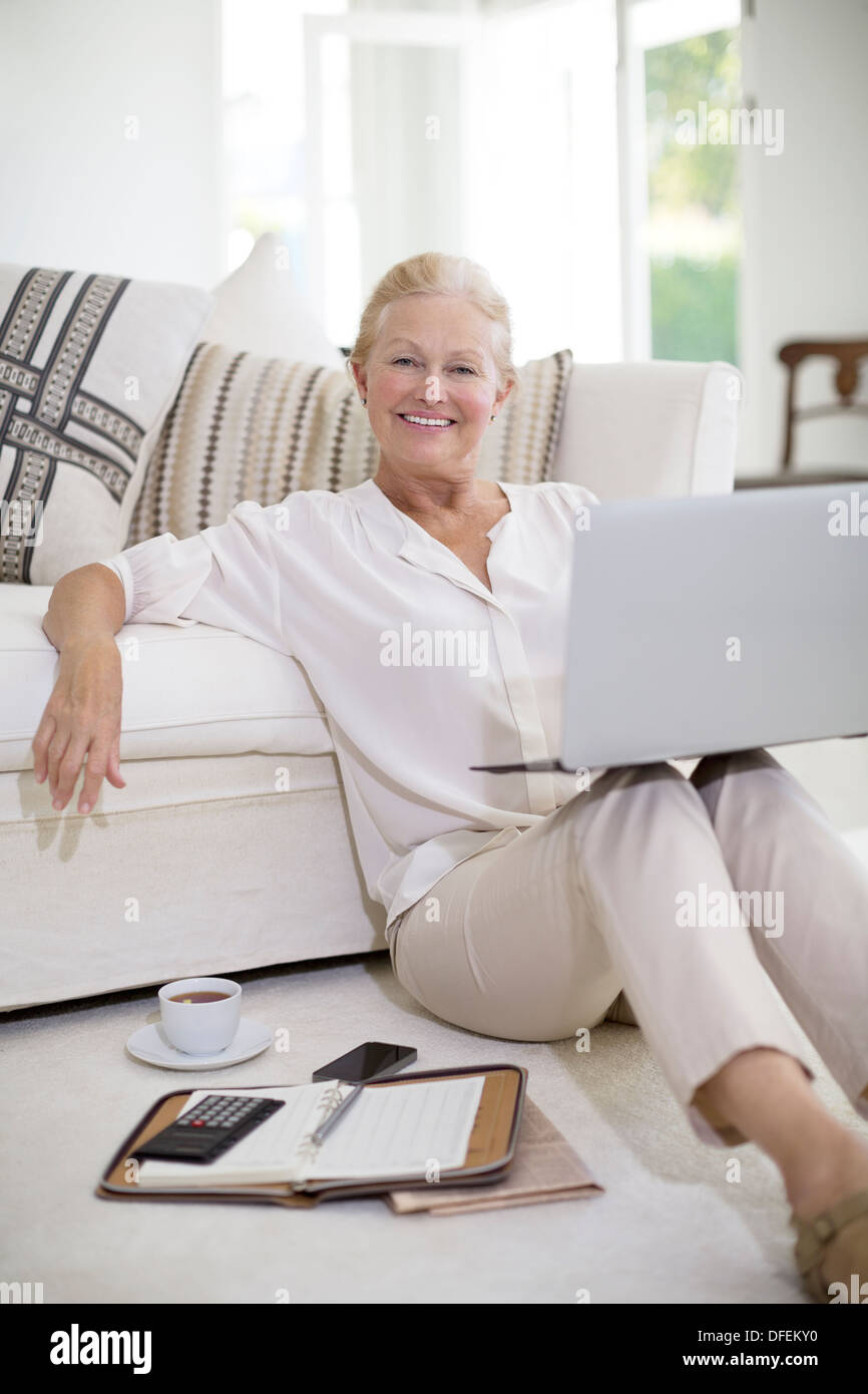 Ältere Frau mit Laptop am Boden des Wohnzimmers Stockfoto