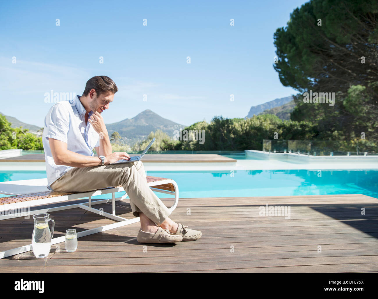 Mann mit Laptop am Pool Stockfoto