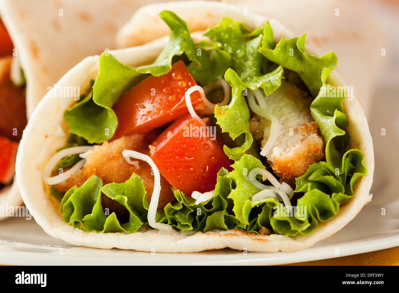 Panierte Chicken in einer Tortilla-Wrap mit Salat und Tomate Stockfoto