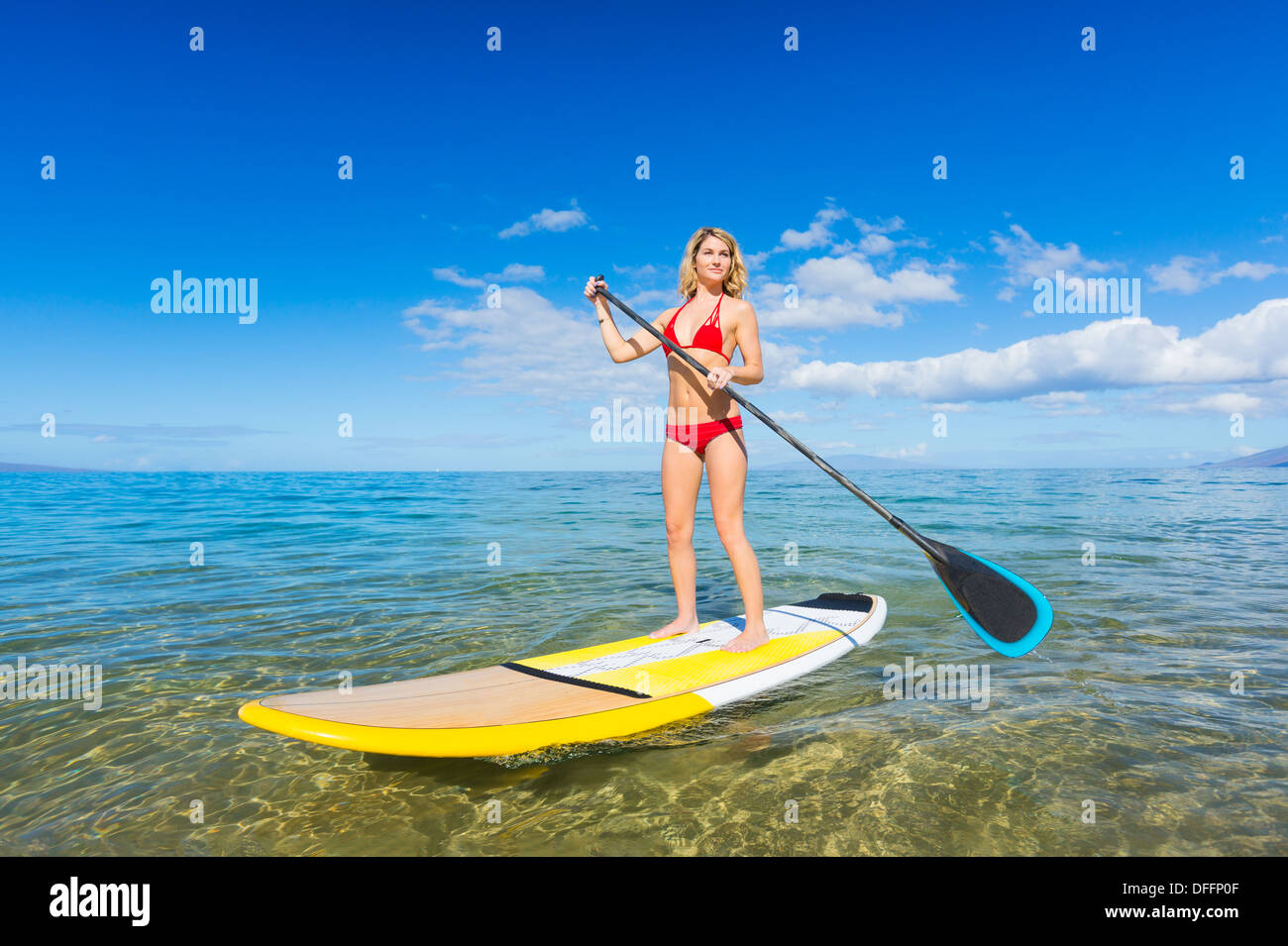 Attraktive junge Frau Stand Up Paddle Surfen In Hawaii, schönen tropischen Ozean aktiv Strand Lebensstil Stockfoto