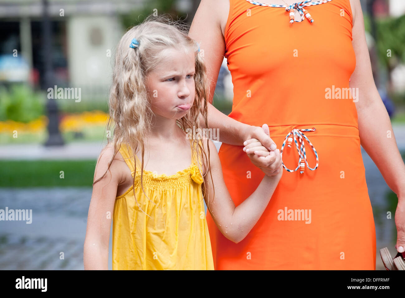 beleidigt kleine Mädchen in nassen Kleid stehen mit ihrer Mutter Stockfoto