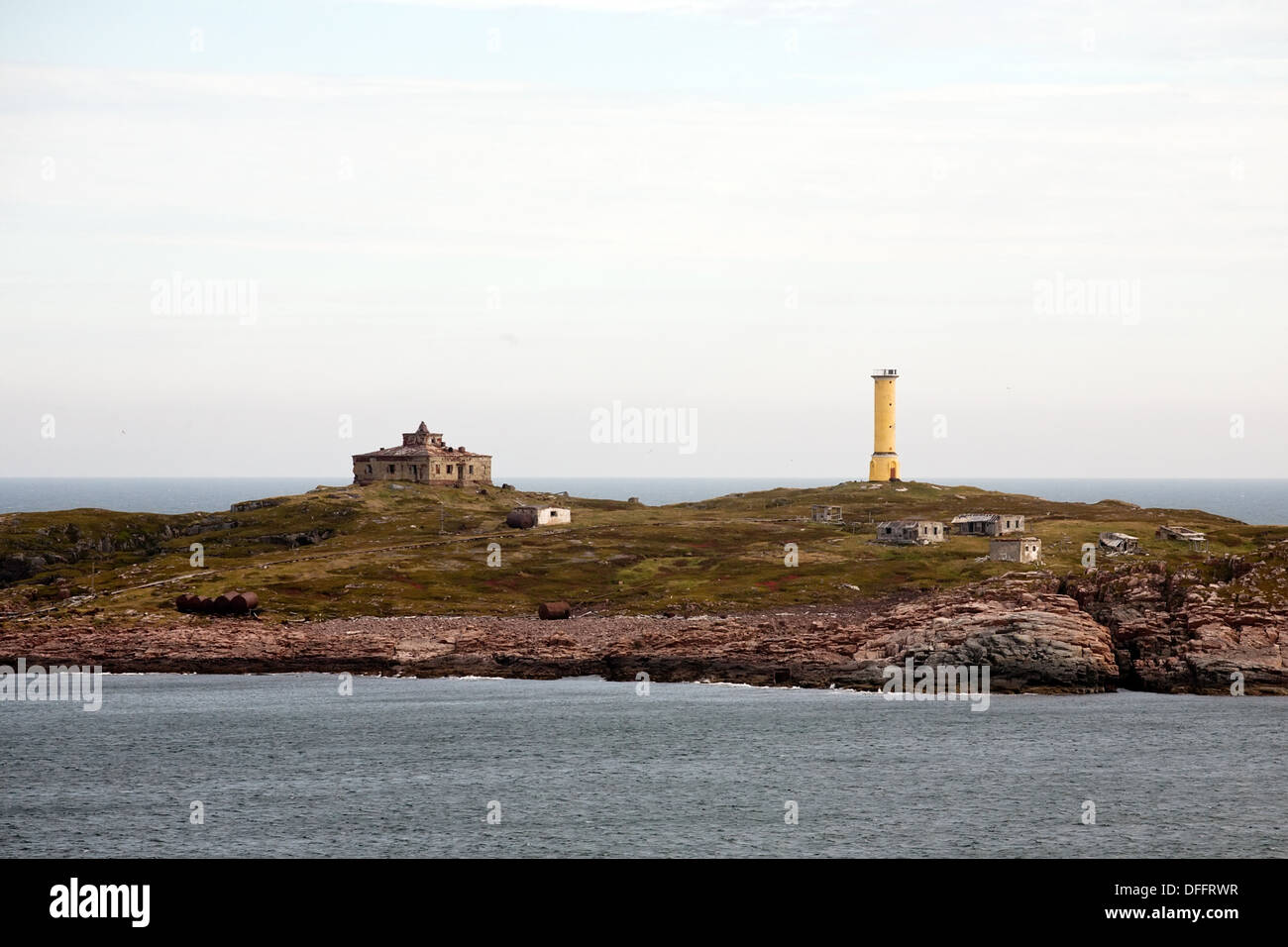gelben Leuchtturm auf kleinen nördlichen Felseninsel unter den verlassenen Häusern Stockfoto