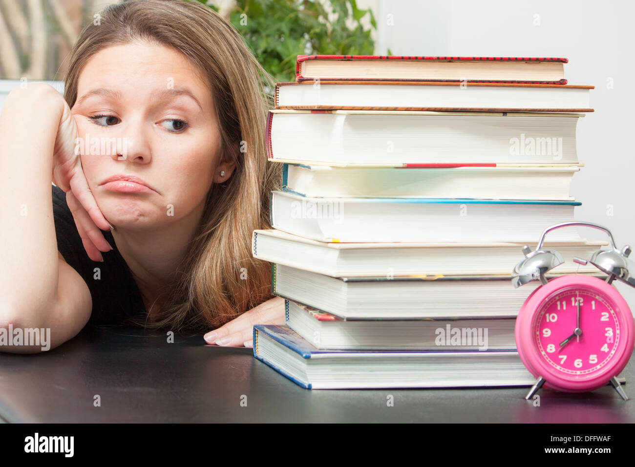 Eine junge Frau blickt auf den großen Stapel Bücher für Prüfung Studie. Zeit Zecken durch erinnerte sie die begrenzte Zeit zur Vorbereitung. Stockfoto