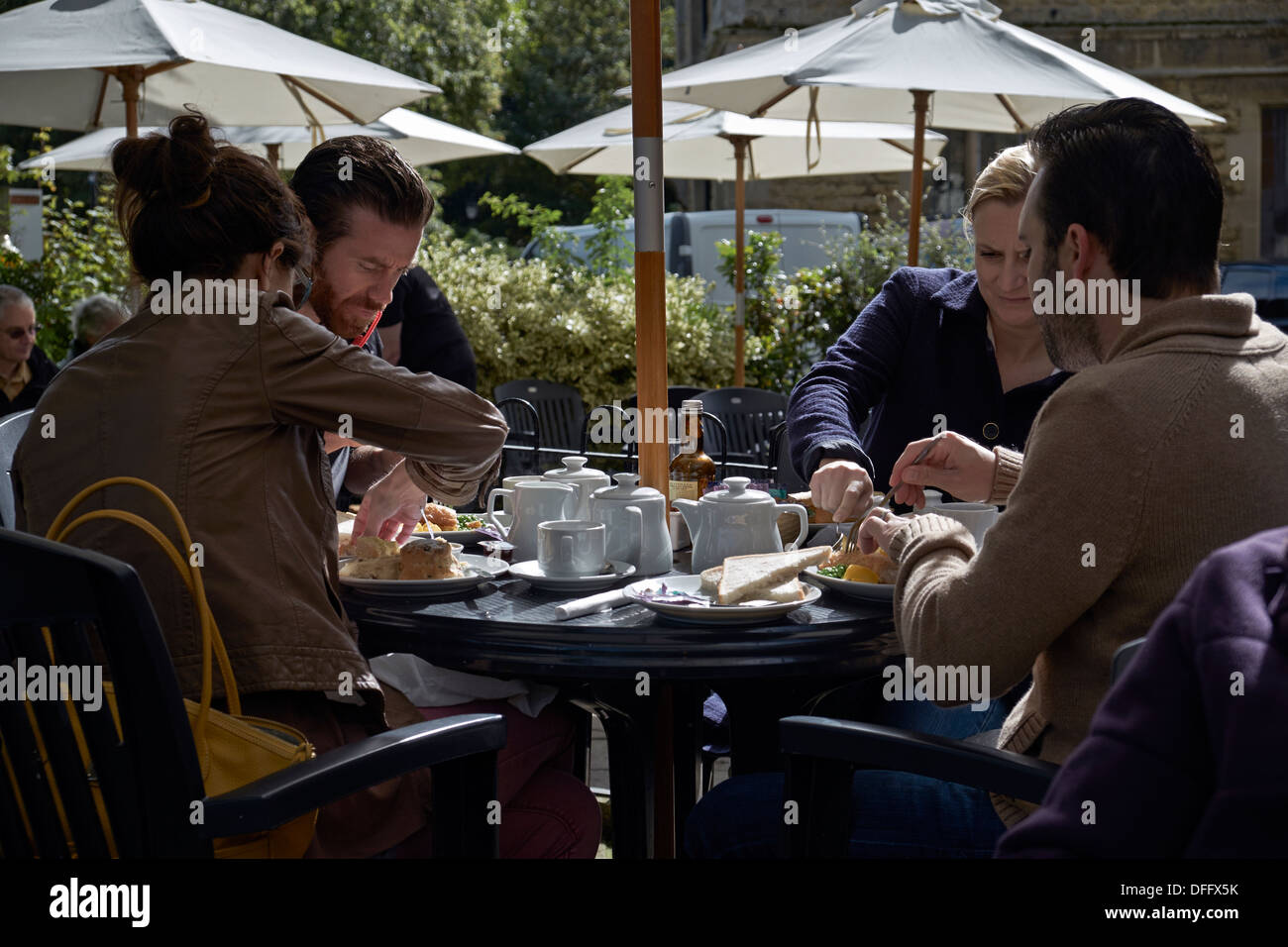 Menschen, die im Freien essen und ein traditionelles Tee und ein leichtes Mittagessen unter Sonnenschirmen genießen. England Großbritannien Stockfoto