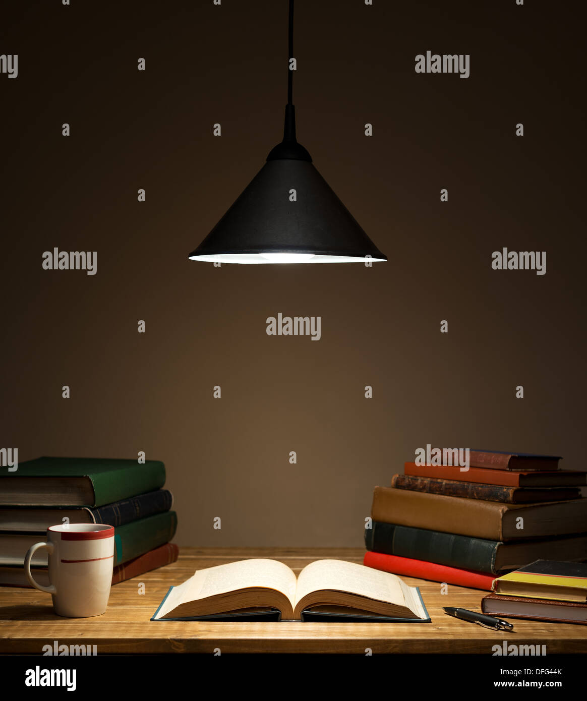 Bücher über Holztisch unter Lampe Stockfoto