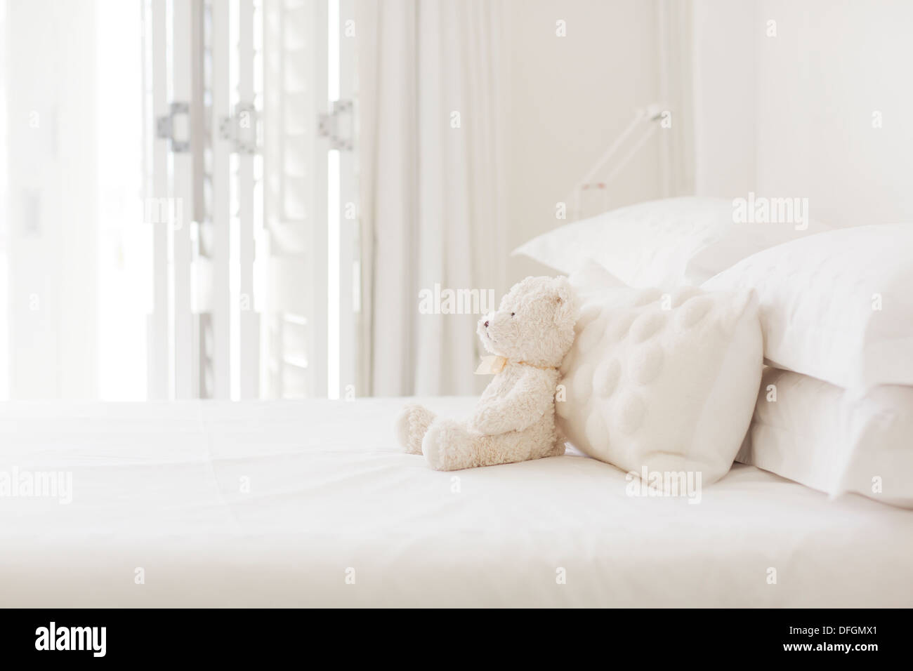 Teddybär und Kissen auf weißen Bett Stockfoto