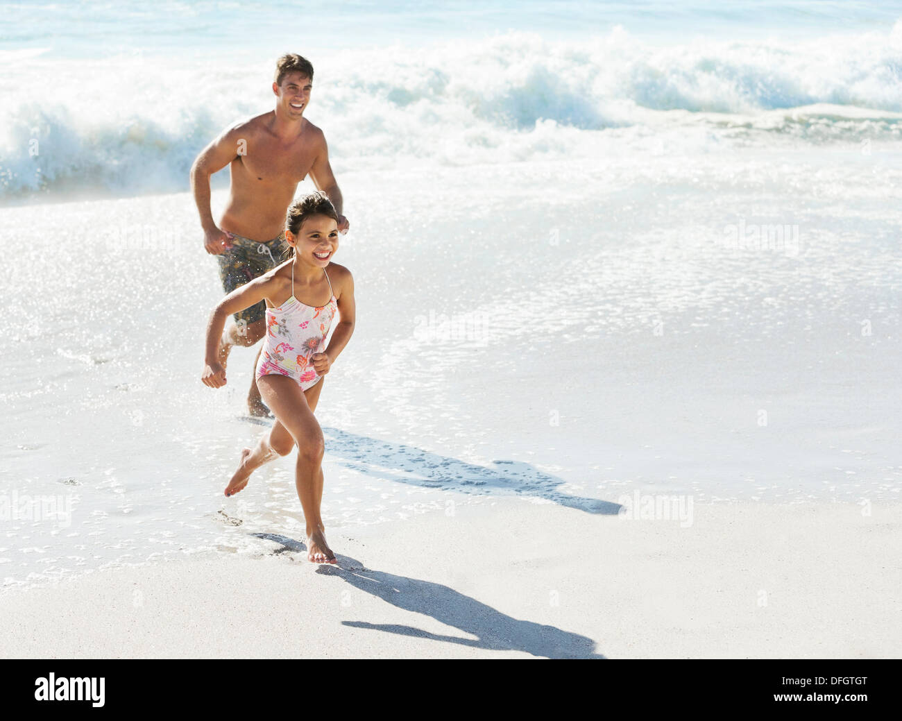Vater und Tochter läuft in Brandung am Strand Stockfoto